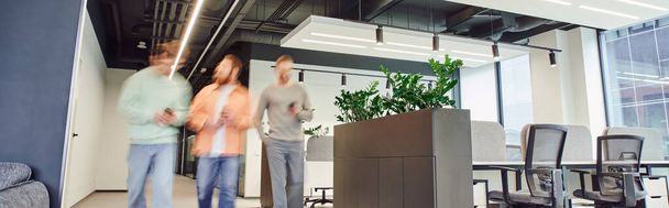 bewegingsvervaging van creatief business team wandelen in hedendaagse coworking ruimte met high tech interieur, modern kantoormeubilair en groene natuurlijke planten, partnerschap en samenwerking, banner - Foto, afbeelding