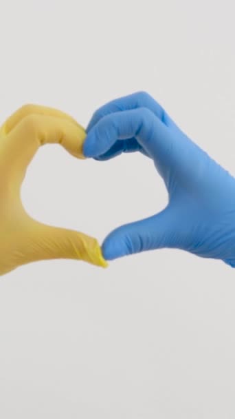 Ręce lekarza w niebieskich rękawiczkach tworzą serce na tle lampy operacyjnej. Pielęgniarka wykazuje oznaki miłości podczas pandemii. Lekarze ratują ludzi. Dowódca-19. Koronawirus. Wysoka jakość - Materiał filmowy, wideo