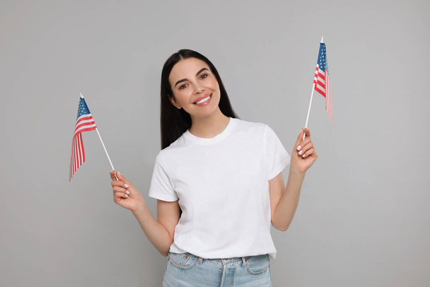 4th of July - Independence Day of USA. Happy woman with American flags on light grey background - Foto, Imagem