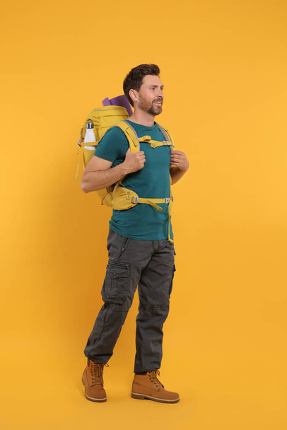 Happy man with backpack on orange background. Active tourism - Fotografie, Obrázek