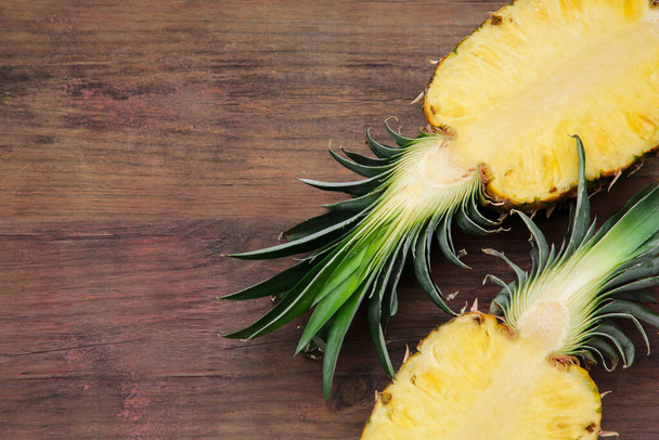 Halves of delicious ripe pineapple on wooden table, flat lay. Space for text - Photo, image
