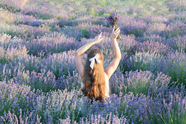 girl walk through lavender field in summer. Stylish summer girl in lavender sunset. girl in lavender field enjoying freedom and nature. summer girl with of lavender flowers on summer day. - Photo, image