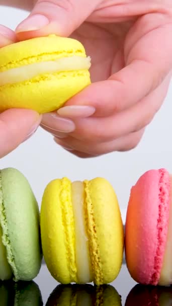 weibliche Hände brechen gelbe Zitronenmacarons Linie von gelben rosa und grünen Makronen bunte Pastellmacarons isoliert auf weißem Hintergrund Macaron bunt  - Filmmaterial, Video