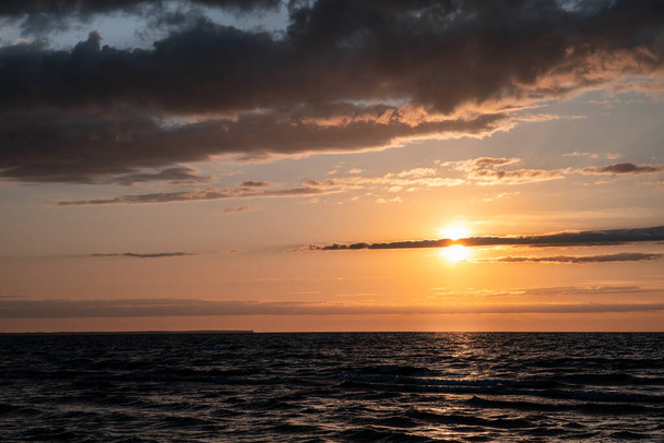 Ostatnie promienie słońca przebijają się przez chmury. Zachód słońca nad wzburzonym morzem. Wysokiej jakości zdjęcie - Zdjęcie, obraz