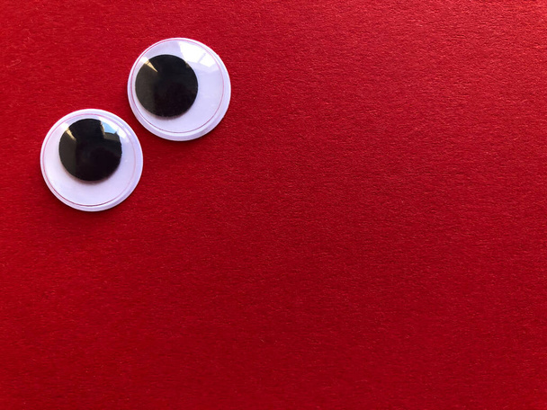 Creative fun background, googly eyes isolated on red background with copy space - Foto, immagini
