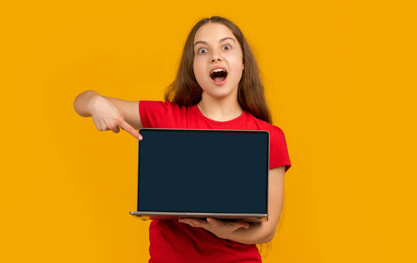 amazed kid with laptop on yellow background. - Foto, Imagem