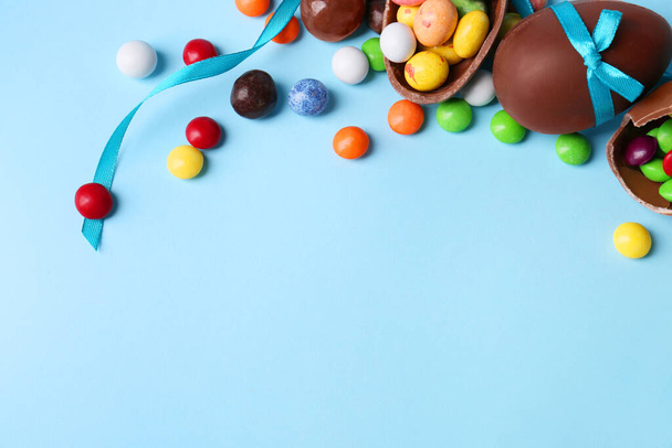 Composition with tasty chocolate eggs and different candies on light blue background, above view. Space for text - Fotoğraf, Görsel