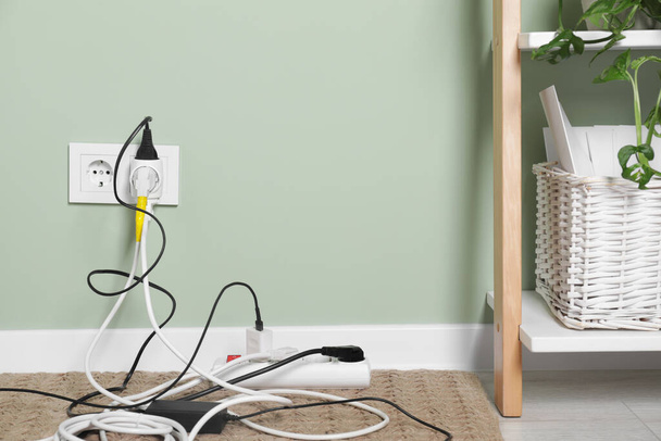 Different electrical plugs in socket and power strip on floor indoors. Space for text - Фото, изображение