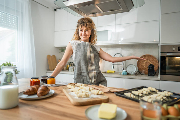 Genç, mutlu, beyaz bir kadın mutfak gülümsemesinde önlük giyiyor. - Fotoğraf, Görsel