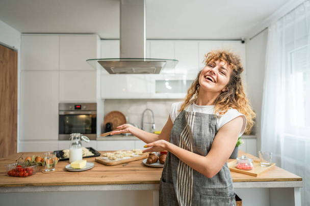 Une jeune femme caucasienne adulte heureuse porte un tablier dans la cuisine sourire - Photo, image