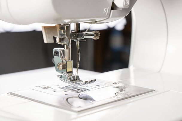 Moderna máquina de coser blanca prensatelas pie primer plano, macro. Equipo de costura, herramienta de trabajo para el negocio del taller, fabricación, ocupación. - Foto, imagen