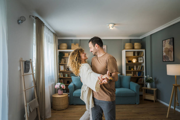 Happy couple adult caucasian man and woman husband and wife dance at home - Photo, Image