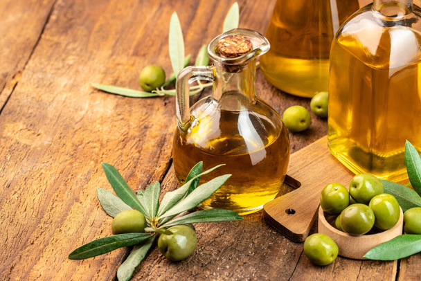 Aceite de oliva y rama de olivo. frascos de aceite de oliva virgen extra sobre un fondo de madera. lugar para el texto. - Foto, imagen