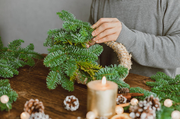 The hands of a male florist makes a New Years drenching from fresh spruce branches, cones and dried fruits. New Years master class. - Фото, изображение