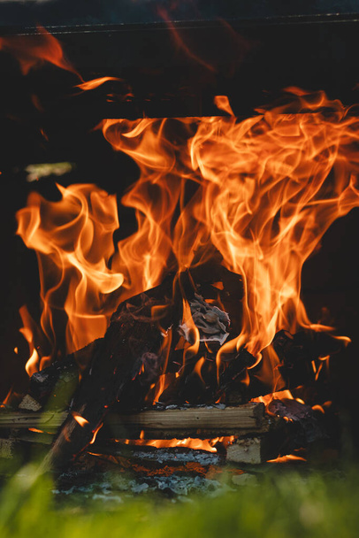 高温下で乾燥した木の割れ目と炎は肉、野菜を焼くための準備花崗岩スラブを加熱するために高さまでホイップします. - 写真・画像