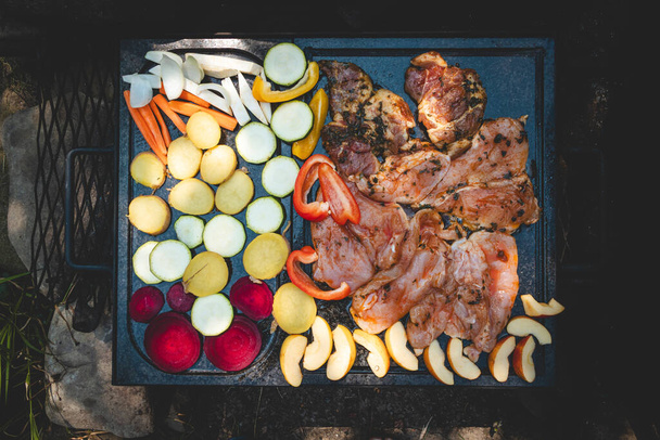 Turkey and chicken breast fillets and vegetables grilling on a granite stone over a hot fire. Preparing meat for dinner. Grilling with friends.  - Photo, Image