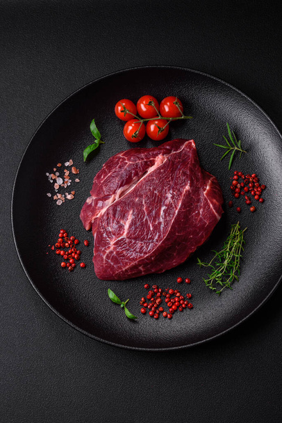 Fresh raw beef steak with salt, spices and herbs on a dark concrete background - Foto, Bild