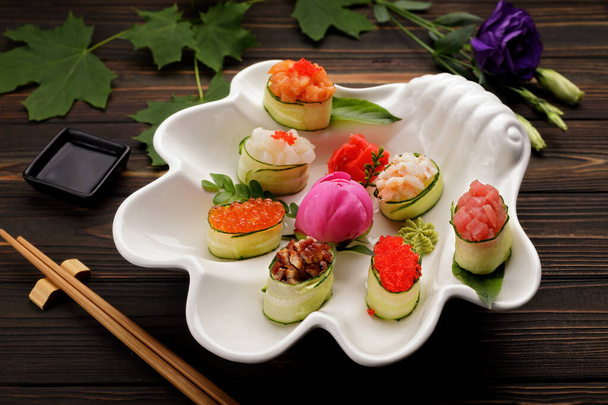 Apetitivo sushi gunkani. en surtido. Salsa de soja, flores fondo de madera - Foto, Imagen