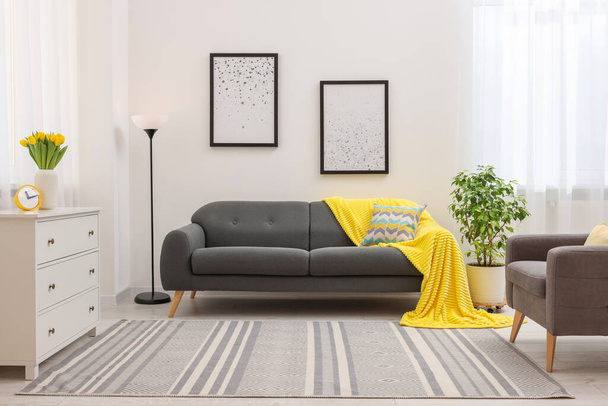 Spring atmosphere. Stylish living room interior with comfortable furniture and bouquet of beautiful yellow tulips - Fotoğraf, Görsel