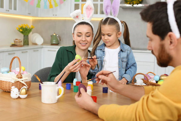 Family painting Easter eggs at table in kitchen - Foto, Imagen