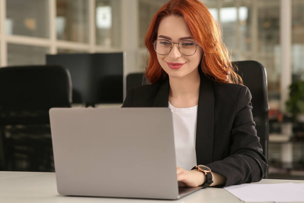 Woman working with laptop at white desk in office - Photo, Image
