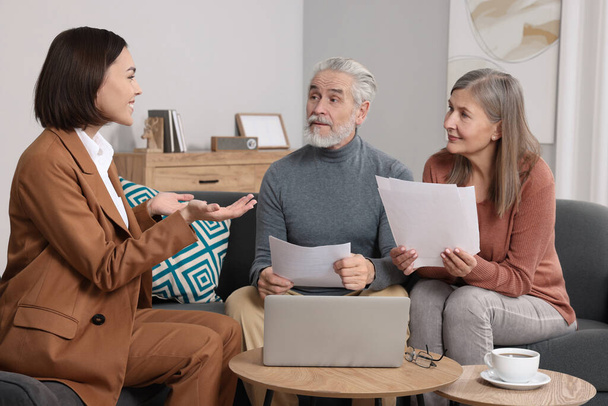 Insurance agent consulting elderly couple about pension plan in room - Φωτογραφία, εικόνα