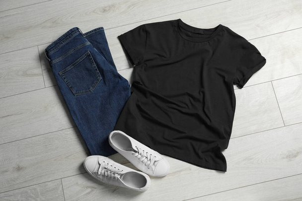 Stylish t-shirt, sneakers and jeans on white wooden background, flat lay - 写真・画像