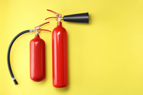 Fire extinguishers on yellow background, flat lay. Space for text - Photo, Image