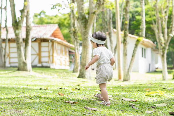 little latin girl walking in the grass of the park, exploring and getting to know the world. - Foto, imagen
