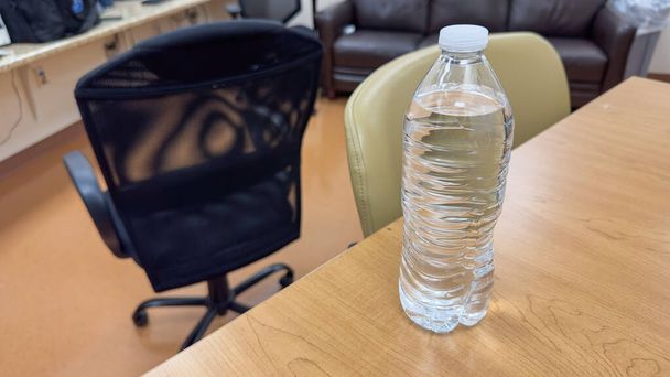 pevně uchopení plastové láhve s vodou, symbolizující dopad na životní prostředí a naléhavost snížení jednorázového plastového odpadu - Fotografie, Obrázek