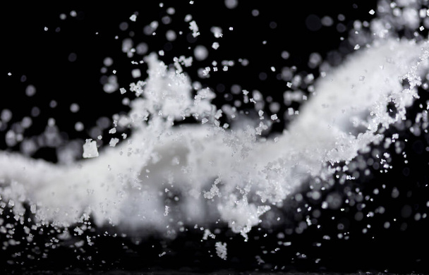 Salzpulver gießen fallen in Schüssel, weißer Salzkristall kochen abstrakte Wolkenfliege. Streusalz spritzt in der Luft, Lebensmittel-Objekt-Design. Schwarzer Hintergrund isoliert selektive Fokusunschärfe - Foto, Bild