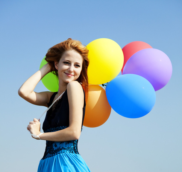 Pelirroja chica con globos de color en el fondo del cielo azul
. - Foto, Imagen