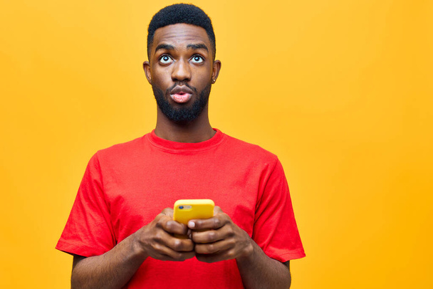 чоловік повідомлення молодий мобільний тисячолітній червоний смартфон бізнес щаслива технологія чорний чоловічий фон модель студії мобільний портрет африканський телефон для дорослих жовтий ізольований - Фото, зображення