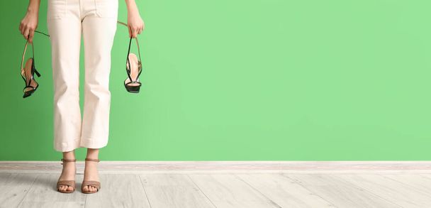 Женщина со стильными сандалиями на высоком каблуке возле зеленой стены. Баннер для дизайна - Фото, изображение