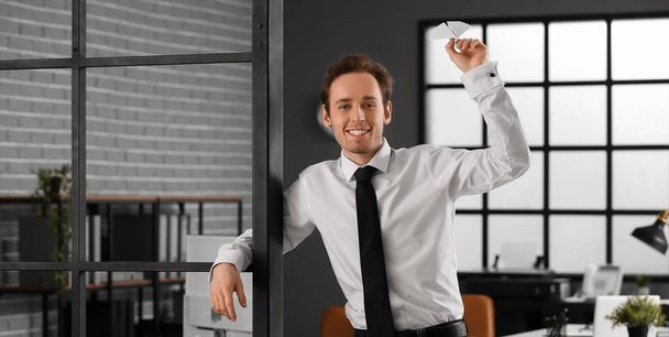 Glücklicher junger Geschäftsmann wirft Papierflieger ins Büro - Foto, Bild