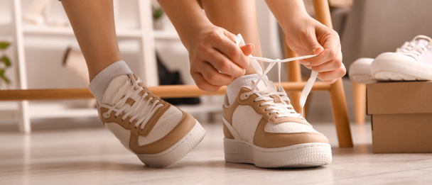 Жінка в стильних кросівок зав'язування взуття мережива в магазині - Фото, зображення
