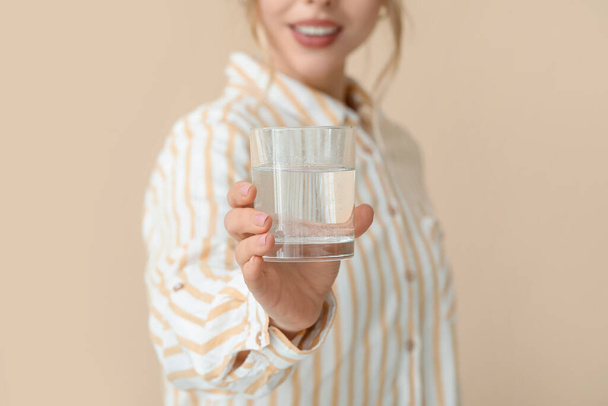 Young woman with dissolved tablet in glass of water on beige background, closeup - Photo, Image