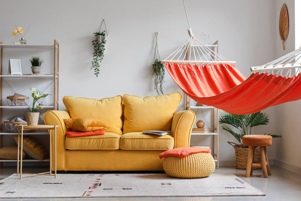 Interno di elegante soggiorno con amaca rossa, divano giallo e tavolino - Foto, immagini