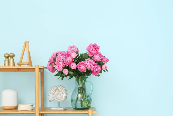 Rózsaszín bazsarózsa váza a polcon a kék fal mellett - Fotó, kép