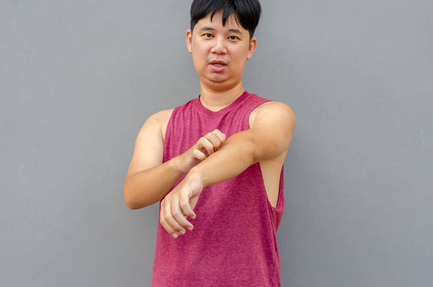 Asian man scratching itch with hand on arm area, health care concept - Photo, Image