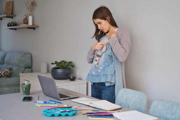 Caucasian woman streaming showing her art design in a denim jacket. Unique clothing designs. - Foto, immagini
