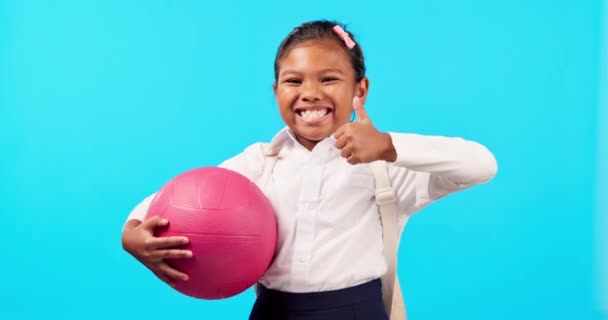 Happy, sports and child with a thumbs up on a blue background for school activities and netball. Smile, success and face portrait of student with a gesture for training isolated on a studio backdrop. - Footage, Video