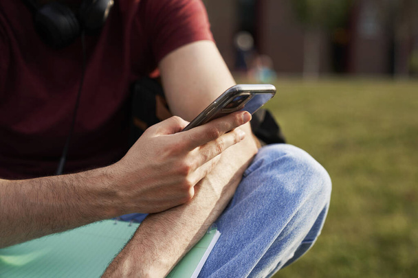 Telefono di navigazione studente irriconoscibile mentre seduto nel campus - Foto, immagini