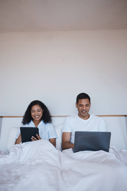 Teknoloji, rahatla ve yatakta sosyal medyada ya da internette birlikte takıl. Happy, gülümse ve genç adam ve kadın sabah yatak odasında dijital tablet ve dizüstü bilgisayara bakıyorlar.. - Fotoğraf, Görsel