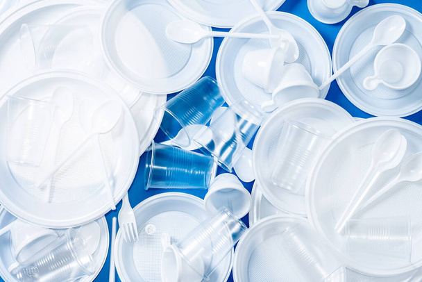 Disposable waste plastic on blue background. - 写真・画像