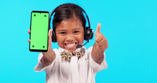 Thank you, portrait of girl with smartphone and headset with her thumbs up in a blue background for success. Achievement or mockup, marketing or advertising and young female person with cellphone. - Footage, Video