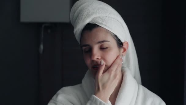 young woman takes care of her facial skin. Doing beauty treatments. Rubbing cream into the skin of the face. Morning Routine. Beauty, Pampering, Home Spa Concept. Skin Care Cosmetic Concept  - Footage, Video