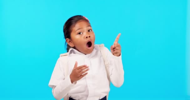 Wow, pointing and comic with a girl on a blue background in studio for an announcement or information. Portrait, smile and you with a happy young female child laughing while making a surprise choice. - Footage, Video