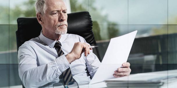 Portret dojrzałego biznesmena sprawdzającego dokument w biurze, wzór geometryczny - Zdjęcie, obraz