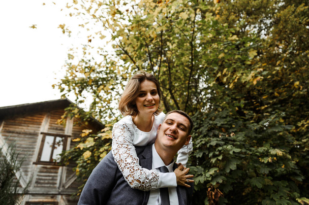 happy bride and groom on the background of a rustic wooden house. wedding concept. autumn time of the year. - Foto, imagen